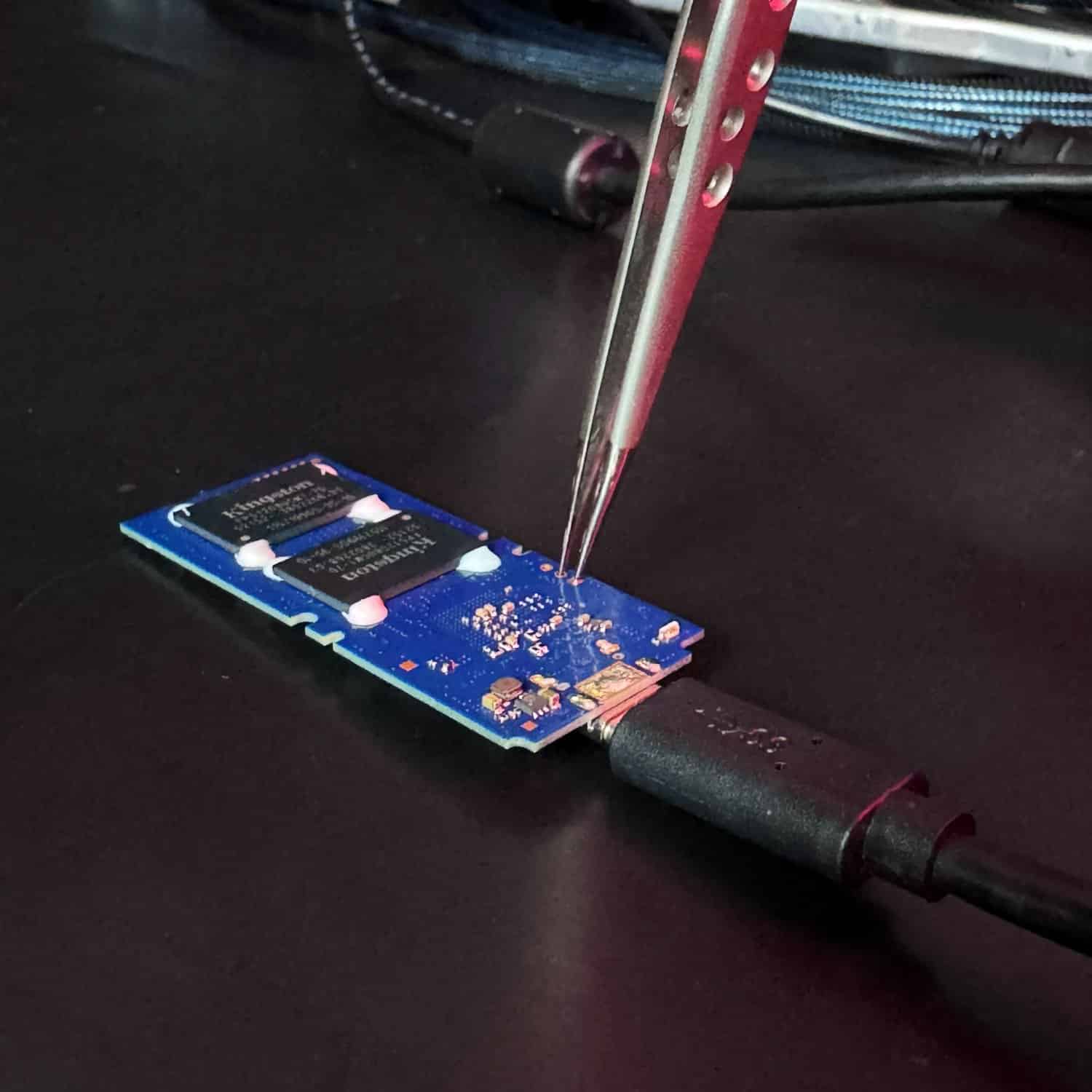 Placa de um SSD M.2 sendo analisada com ponta de prova no laboratório da UTI dos Dados