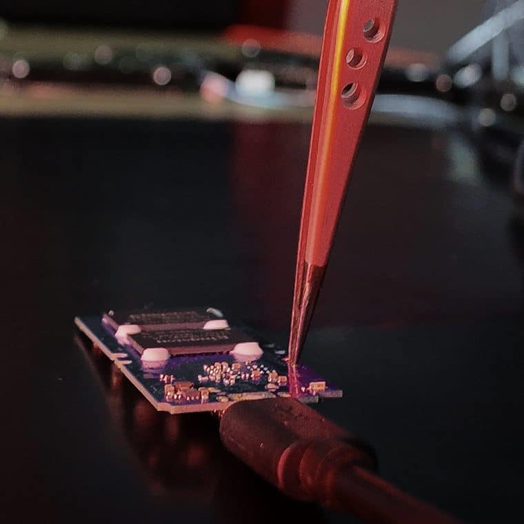 SSD 17 Placa de SSD sendo examinada com pinça na bancada do laboratório da UTI dos Dados